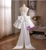 Back view of a white satin homecoming dress featuring a lace-up closure and a sleek, minimalist silhouette.