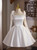 White satin A-line homecoming dress featuring detachable sheer sleeves with bow accents at the shoulders, a square neckline, and a flared knee-length skirt.