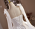 Versatile white satin homecoming dress worn without the sheer sleeves, showcasing the clean square neckline, lace-up back, and a dainty bow at the natural waist.