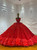 A strapless red sequin ball gown that commands attention, its firelit tulle bodice shimmering with dense sparkle against a full, dramatic skirt.