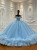 A blue off-shoulder tulle ball gown that shimmers like a night sky, its sequin embroidery scattered across the bodice like a constellation of stars.