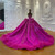 The back of this strapless fuchsia gown features a lace-up corset for a perfect fit, with the beaded bodice flowing into a voluminous tulle train.