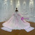 Back view of a pink princess wedding dress featuring a lace-up corset back, intricate sequin and beaded appliques, and a sweeping tulle train