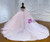 Back view of a pink wedding dress showcasing a beautiful large bow at the waist, a lace-up corset back, and a sweeping tulle train.