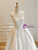 Close-up of intricate floral appliqués on the bodice of a white off-the-shoulder satin wedding dress