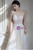 Bride wearing white tulle v-neck wedding dress with appliqués and floor-length hem