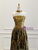 Close-up detail of the ruched, strapless bodice and the off-shoulder draped sleeves of the bronze-gold evening gown.