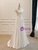 Front view of the white satin A-line pleated bridal gown.