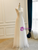 Profile view showing the soft, sweeping hemline and the relaxed fit of the gown.