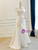 Side profile highlighting the architectural drape and elegant sweeping hemline.