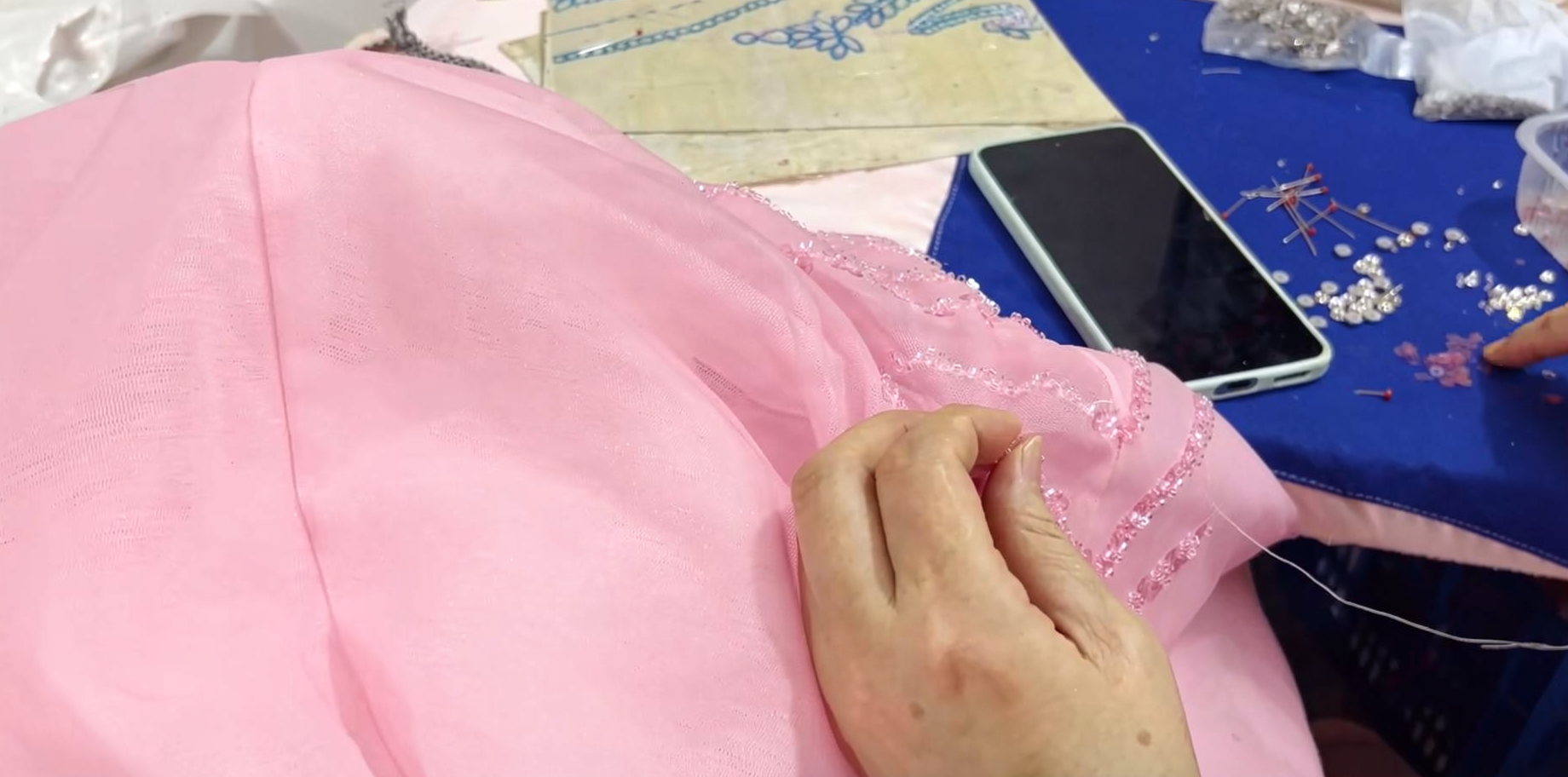 Applying Tiny Seed Beads to Pink Ball Gown Applying tiny seed beads by hand to pink ball gown fabric