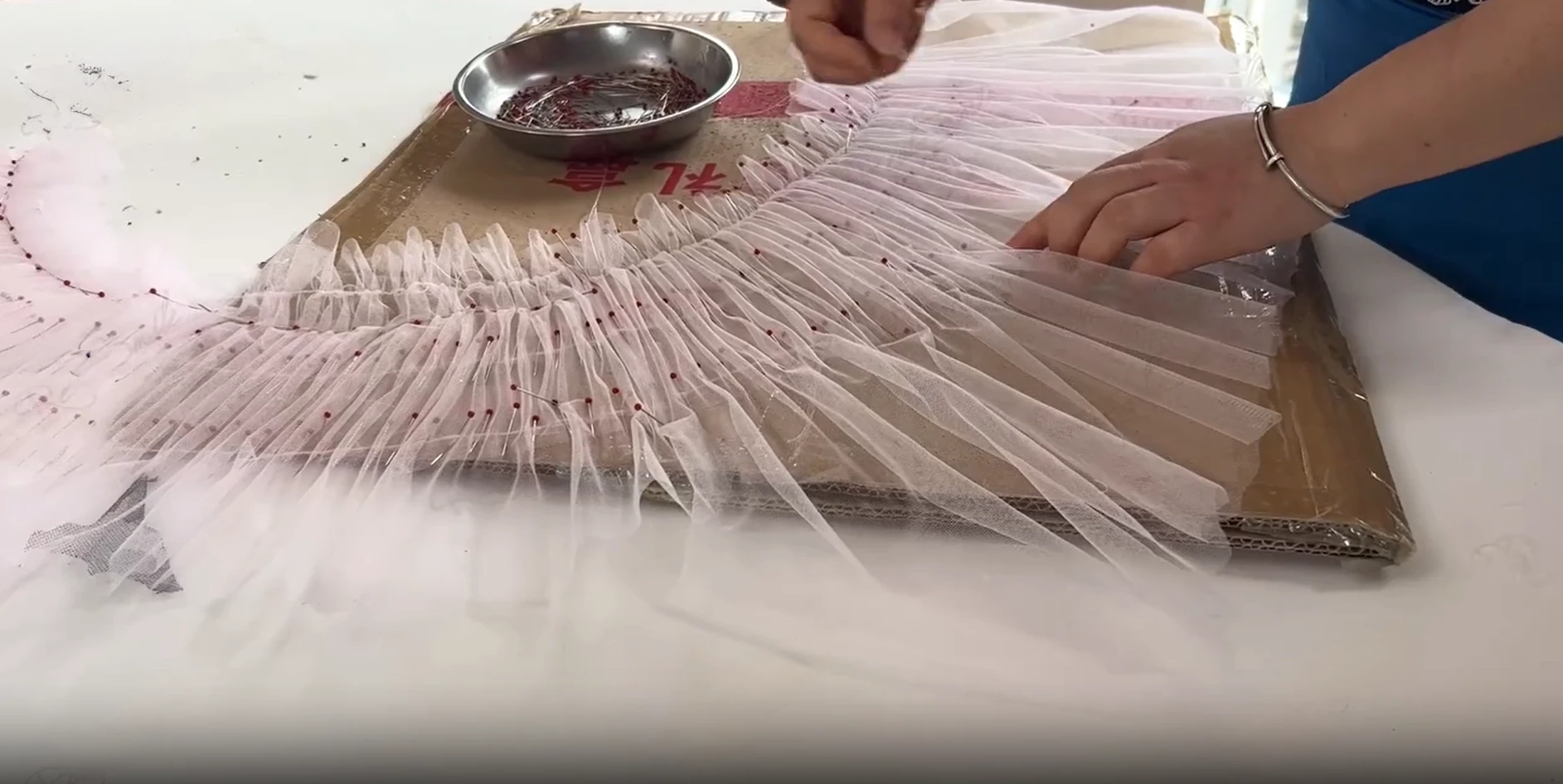 Artisan arranging delicate pink tulle layers for a couture floral prom gown