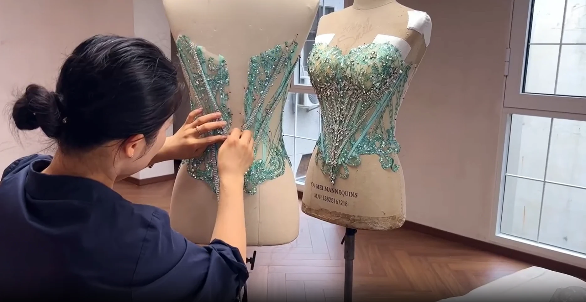 Hand beading process on the mint green sequined ball gown in the atelier