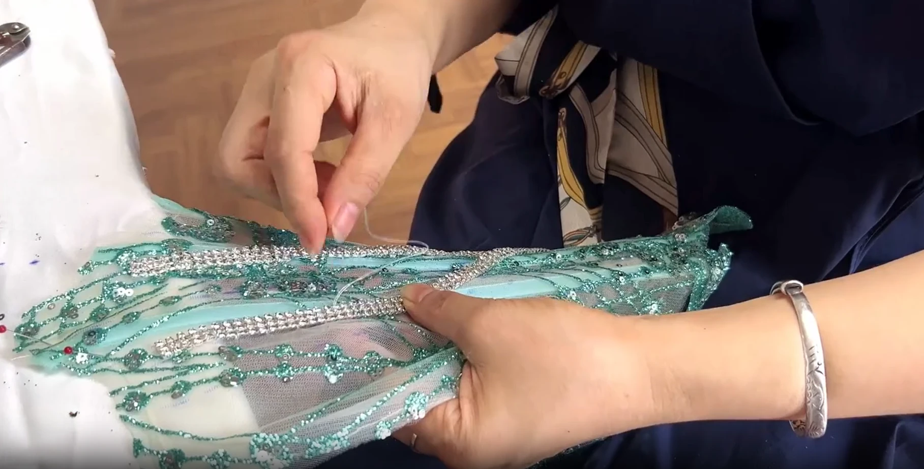 Beader positioning rhinestone chain on mint green ball gown tulle