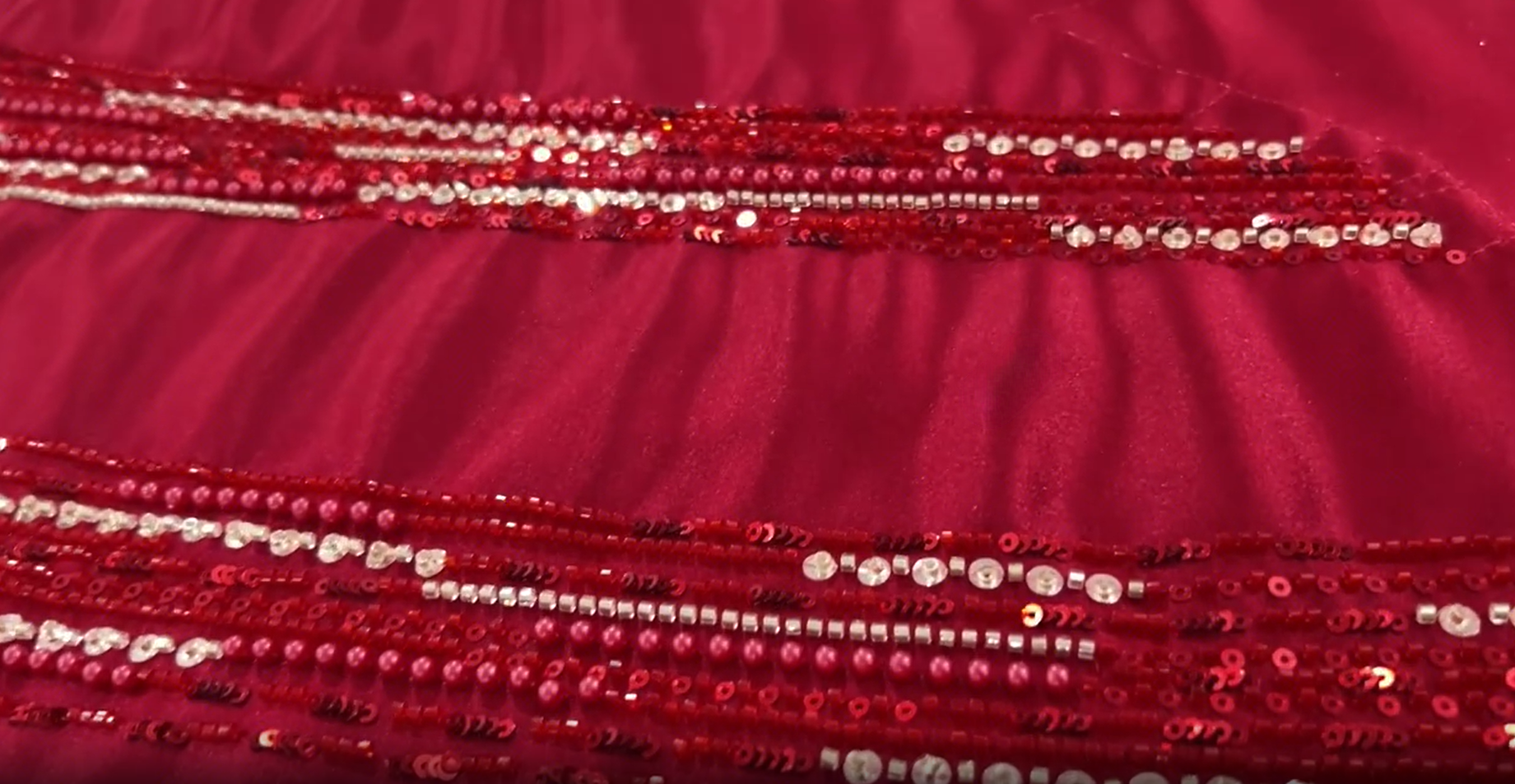 Close-up of red glass beads silver crystals and sequins hand-sewn onto satin