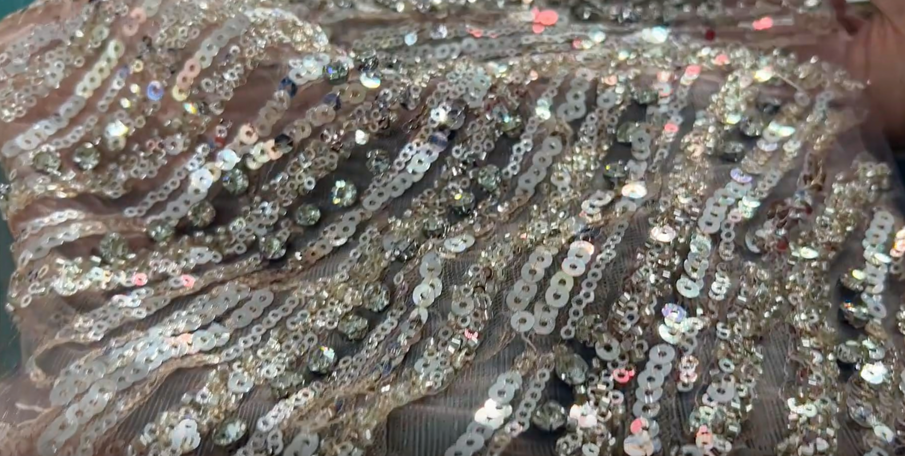 Ultra-close-up shot of the champagne pink sequins and hand-beaded flower centers on the finished prom dress, showcasing the intricate detail