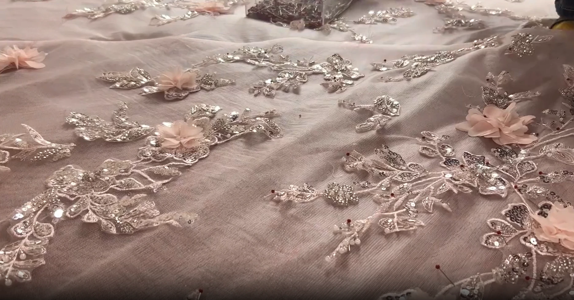 Close up of beaded lace tulle and three dimensional pink floral gown embellishment