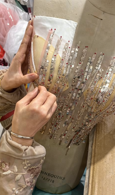 Artisan matching the champagne pink and rose gold thread and sequin colors against the tulle fabric for the gown