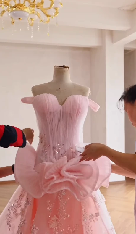Close view of a handcrafted three dimensional fabric bow on a pink gown bodice