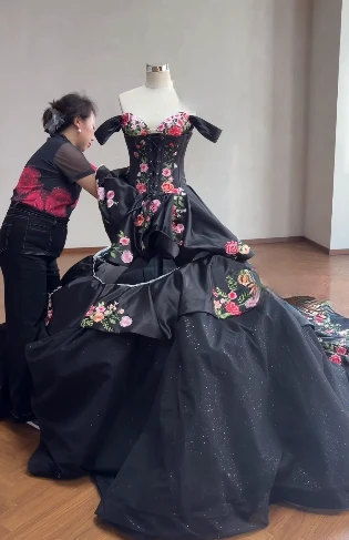 Final adjustments being made to the black gown on a dress form