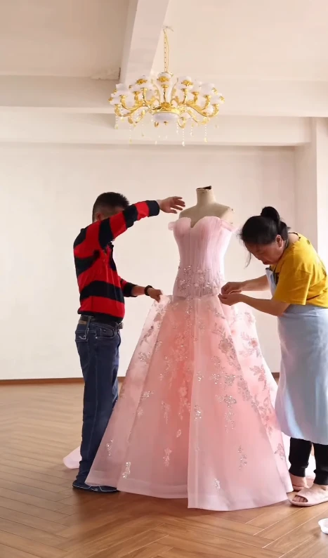 Fitting a voluminous pink tulle ball gown onto a dress form in a studio