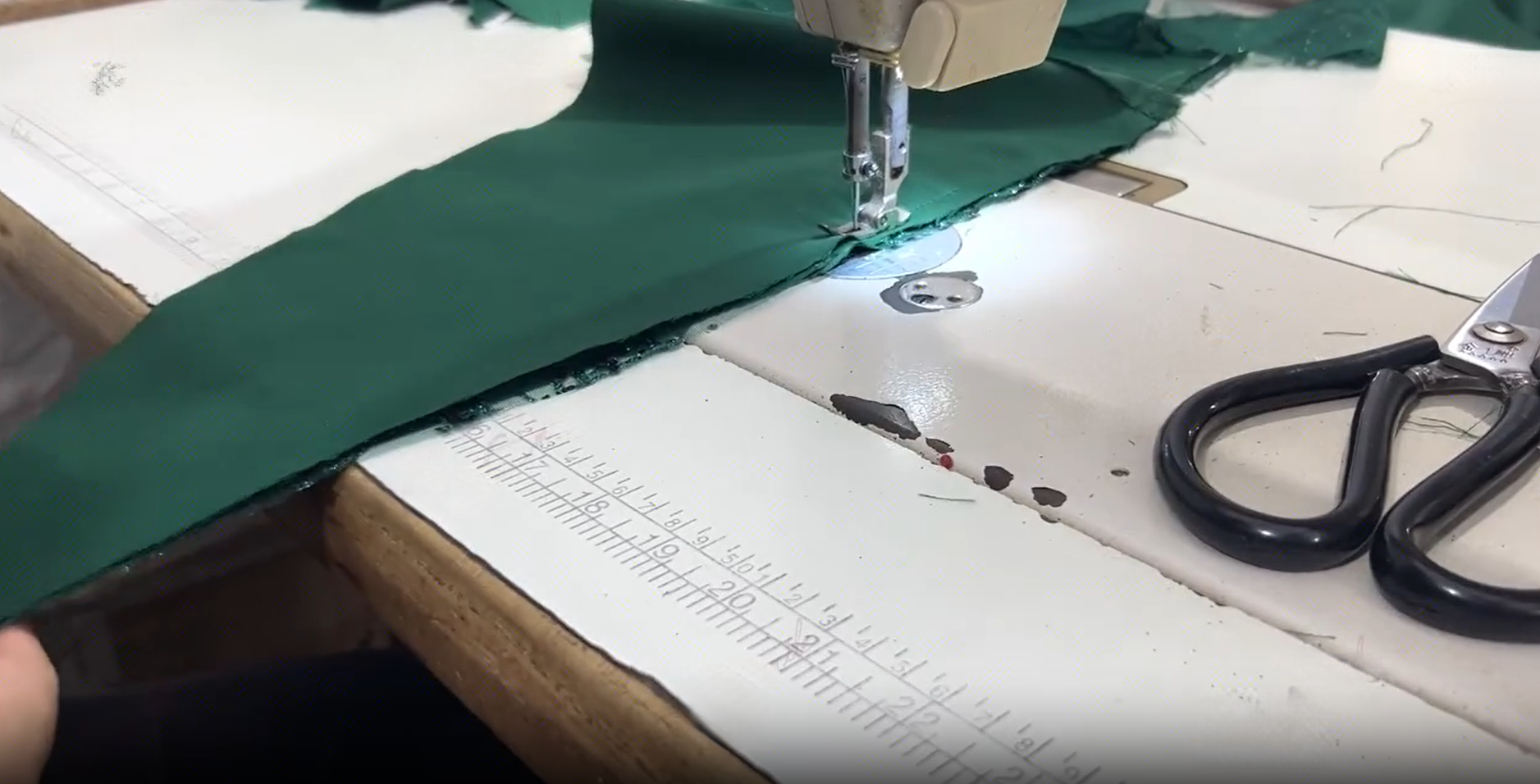 Green satin fabric being sewn on industrial machine