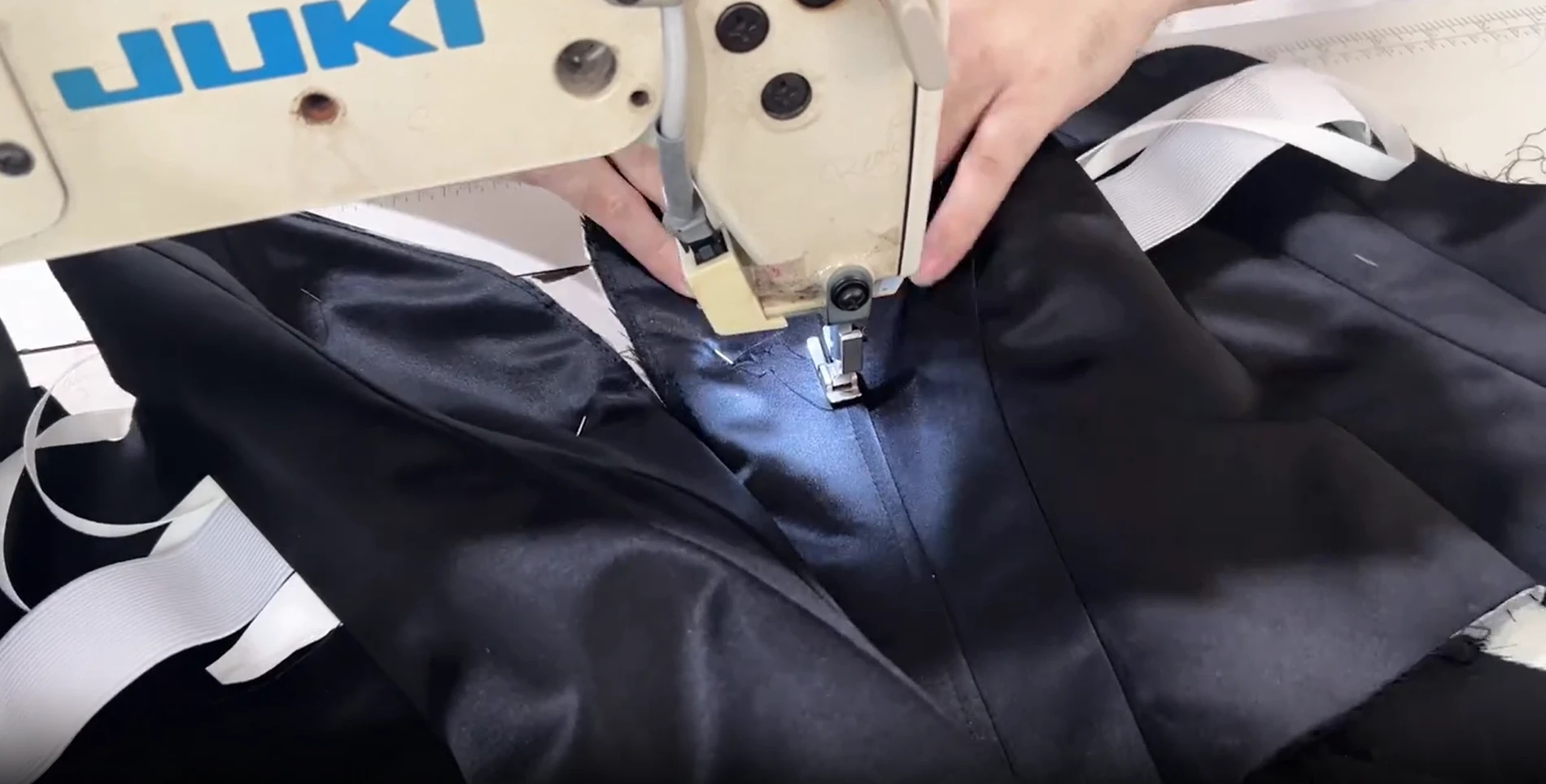 Embroidered satin being carefully guided through the needle