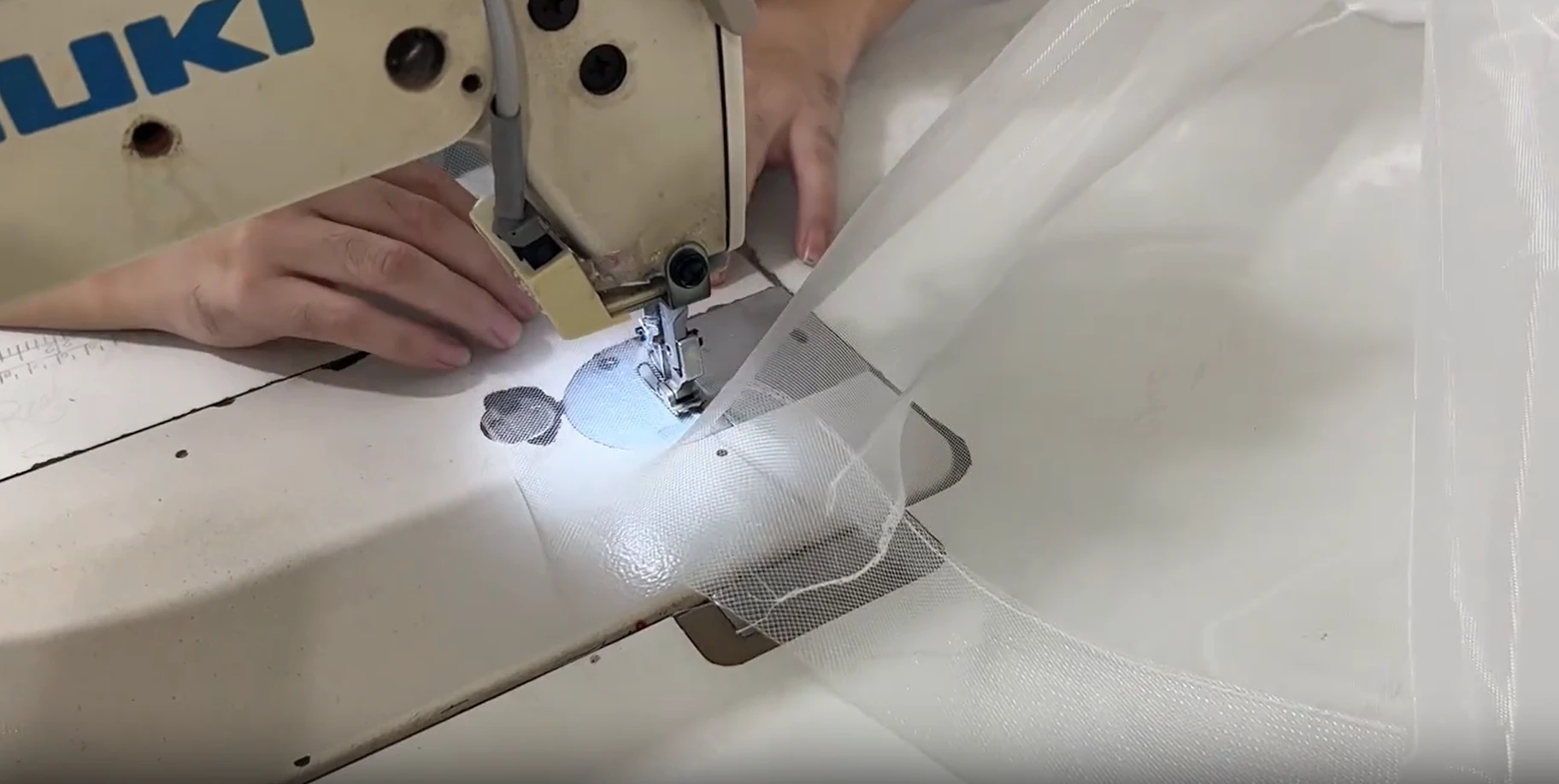 Guiding white fabric carefully through the sewing machine