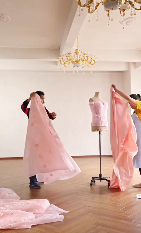 Artisan hand assembling a blush pink ball gown on a mannequin