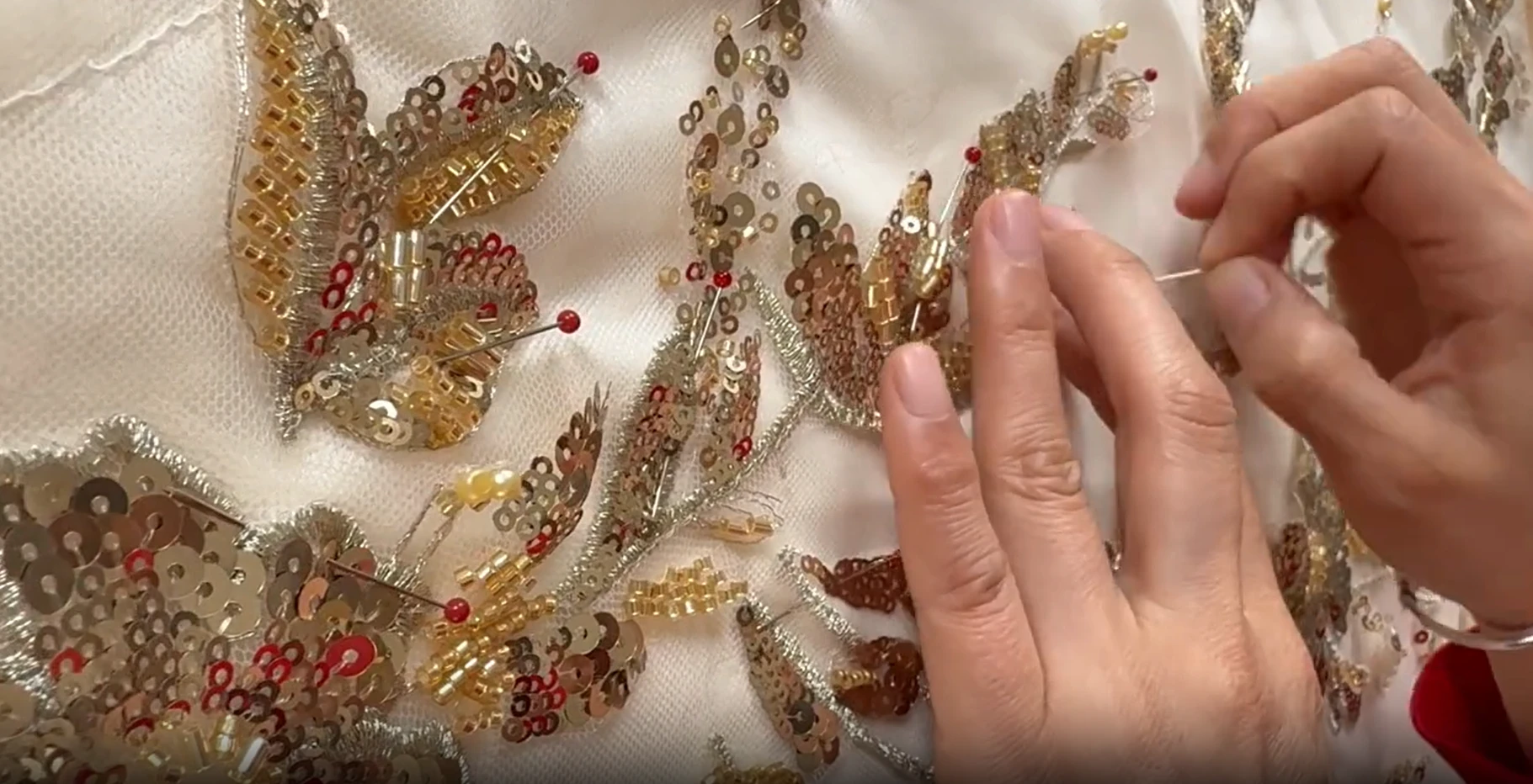 Close up of hand embroidery with gold and red beads Close up of hand embroidery with gold and red beads