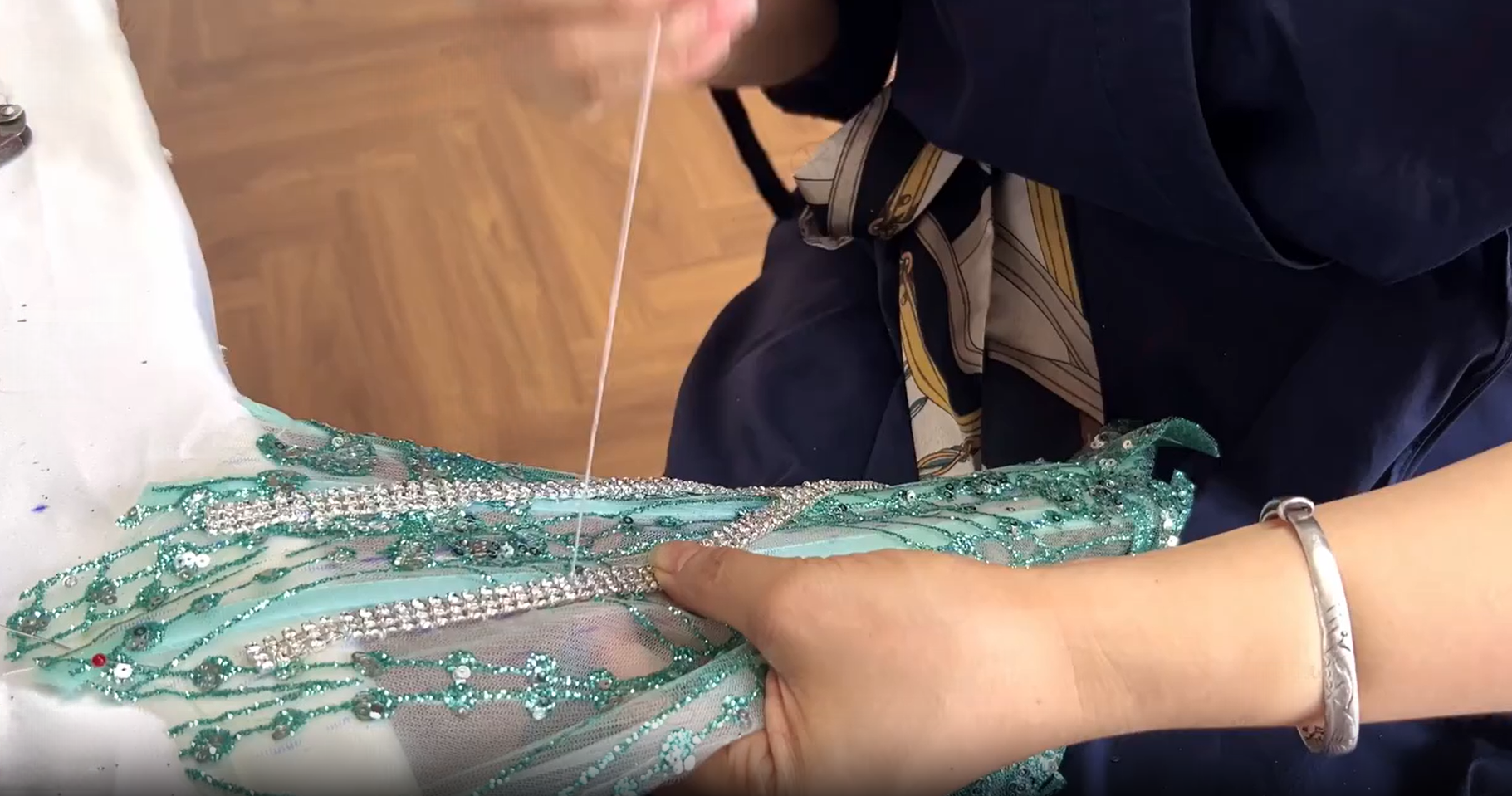 Hand sewing crystal chain onto the mint green ball gown bodice