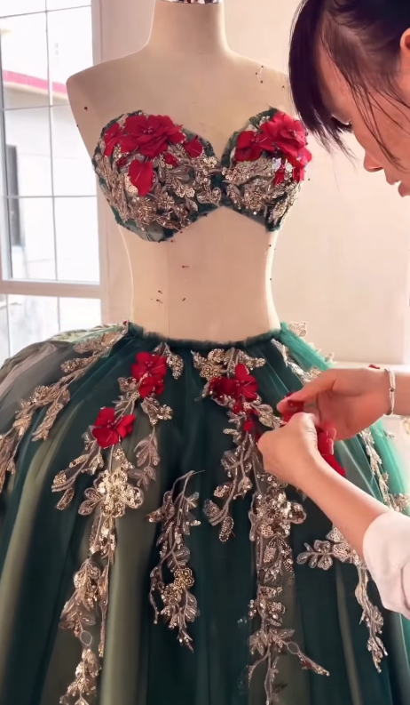 Hand sewing gold and red decorations on gown