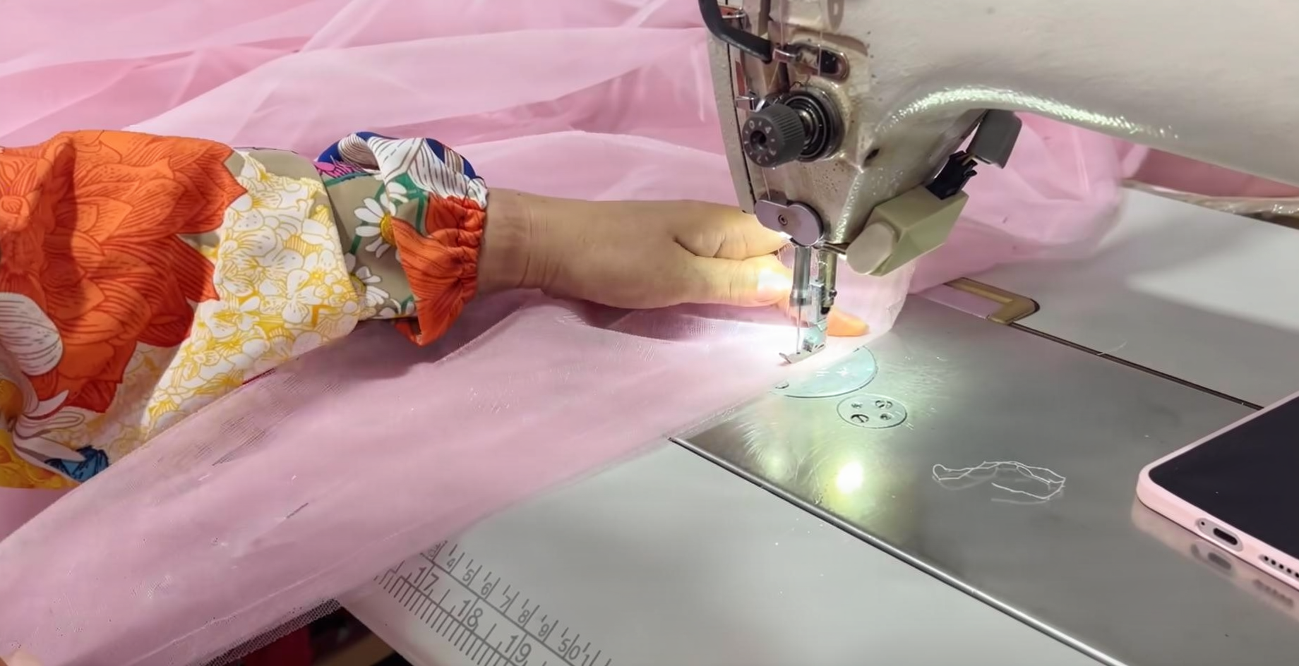 Hand sewing delicate pink tulle fabric for a beaded ball gown