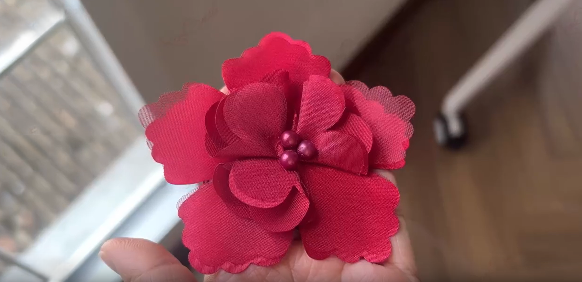 Handmade red fabric flower being inspected