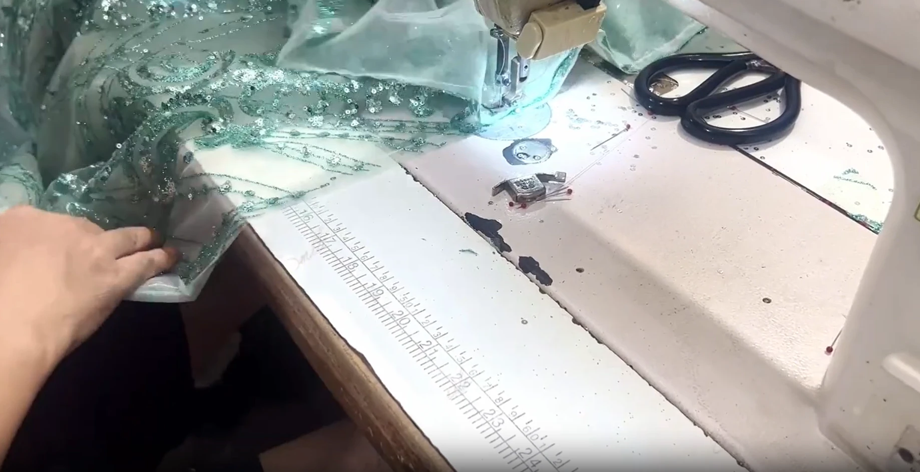 Industrial sewing machine assembling the layered tulle of the green ball gown