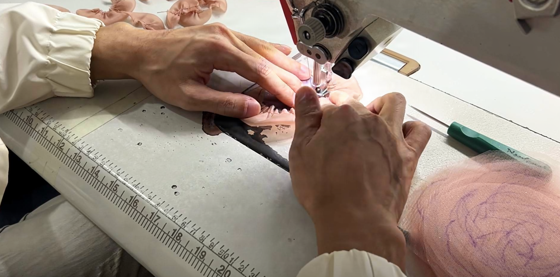 Industrial sewing machine used to stitch the foundation layers of the champagne pink prom dress on the worktable