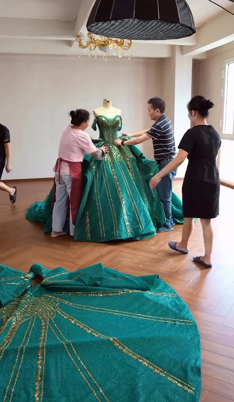 Workshop team fitting structured emerald ball gown
