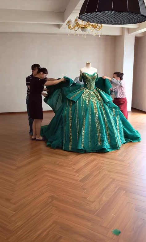Final fitting of completed green ball gown