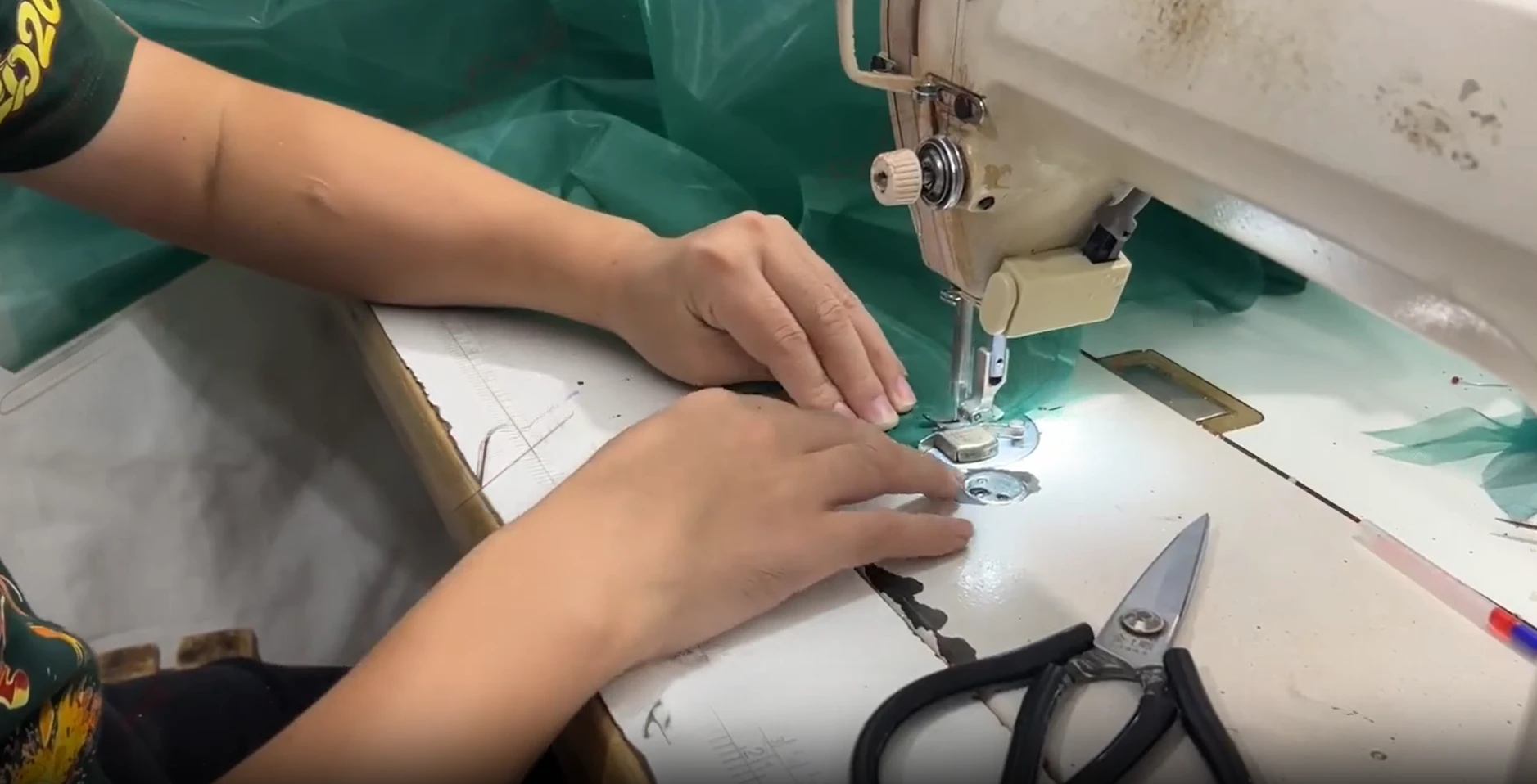 Tailor working with emerald gown fabric panels
