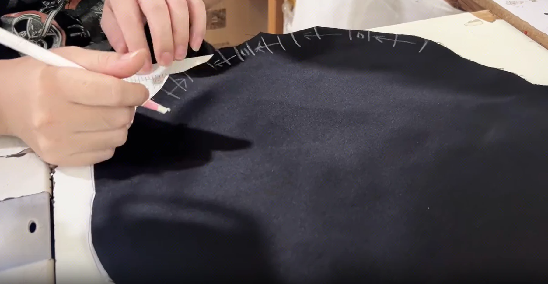 Tailor marking seam placement on black fabric