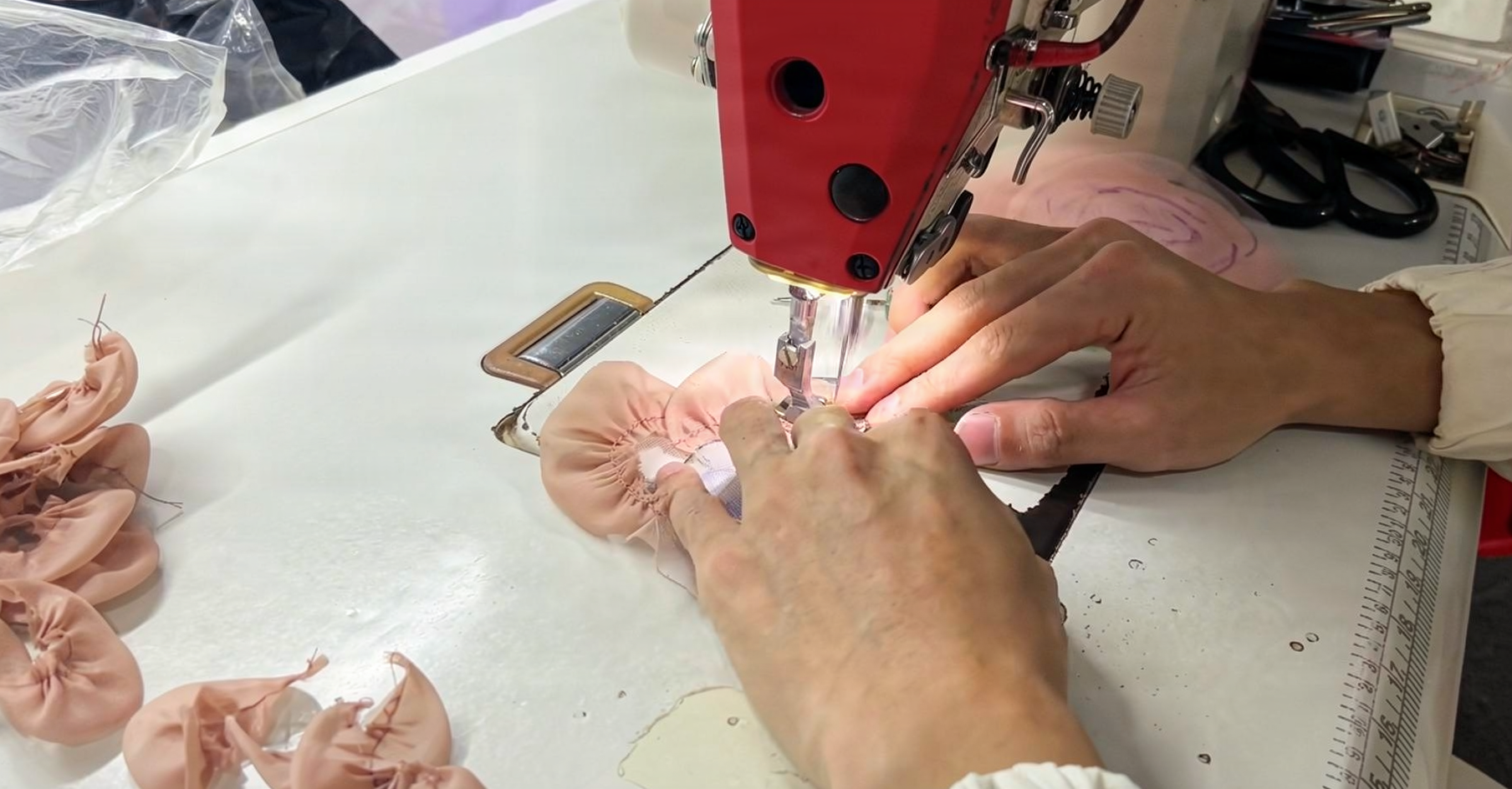 Couture seamstress sewing the champagne pink tulle panels on an industrial machine in the atelier