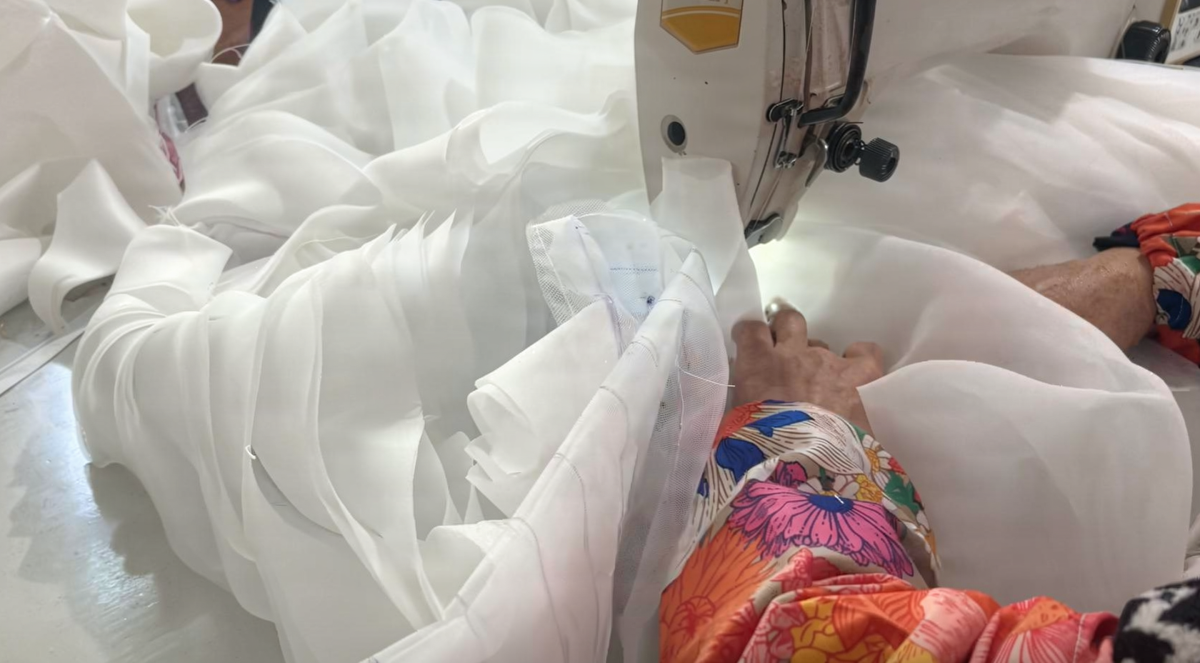 Sewing layered ivory tulle petals to create three dimensional roses for a wedding skirt