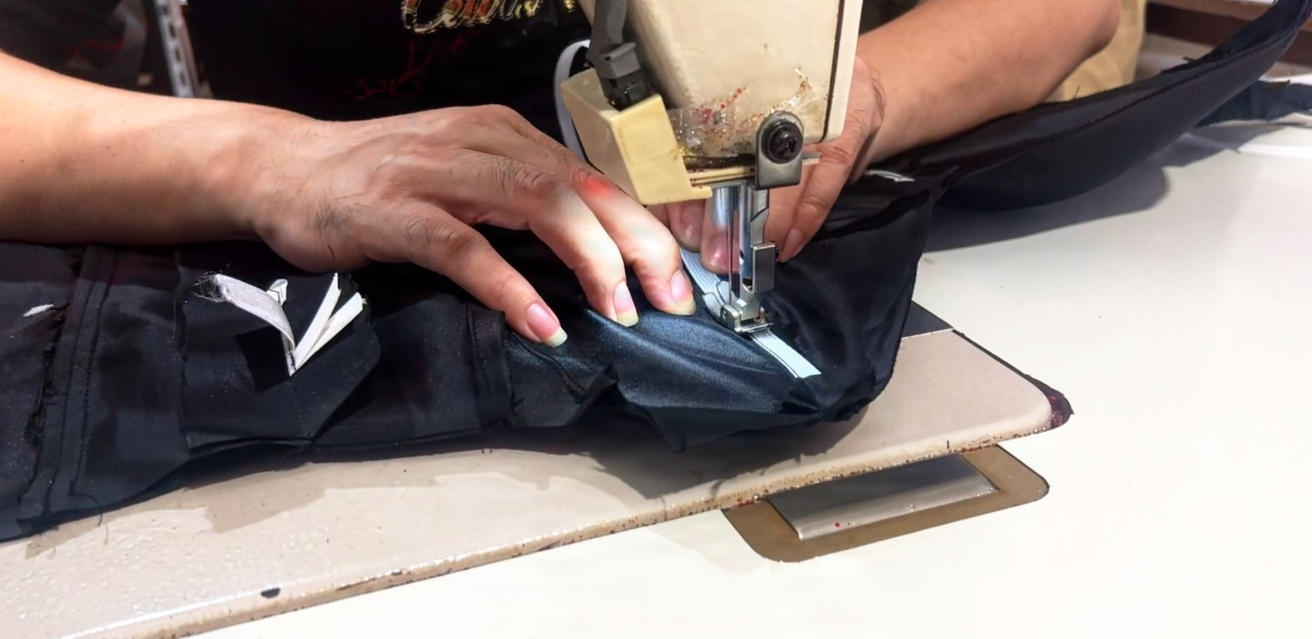 Sewing machine stitching a black velvet ball gown skirt panel