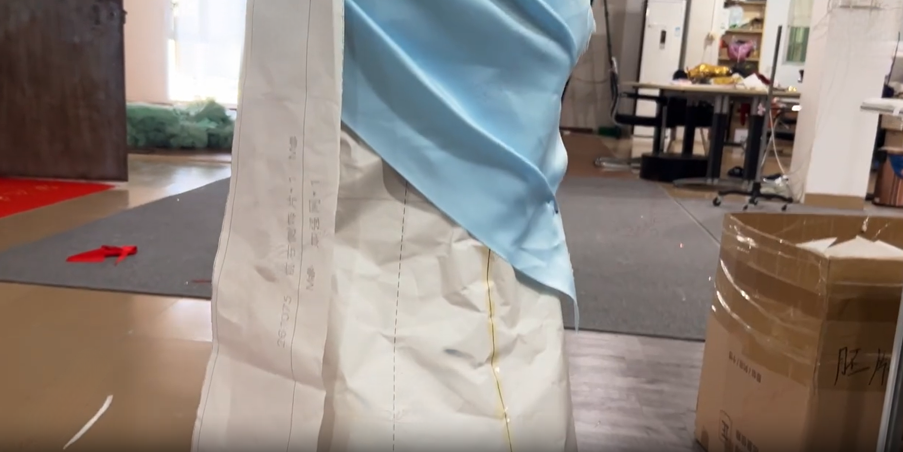 Dressmaker testing the shoulder drape for a red satin formal gown
