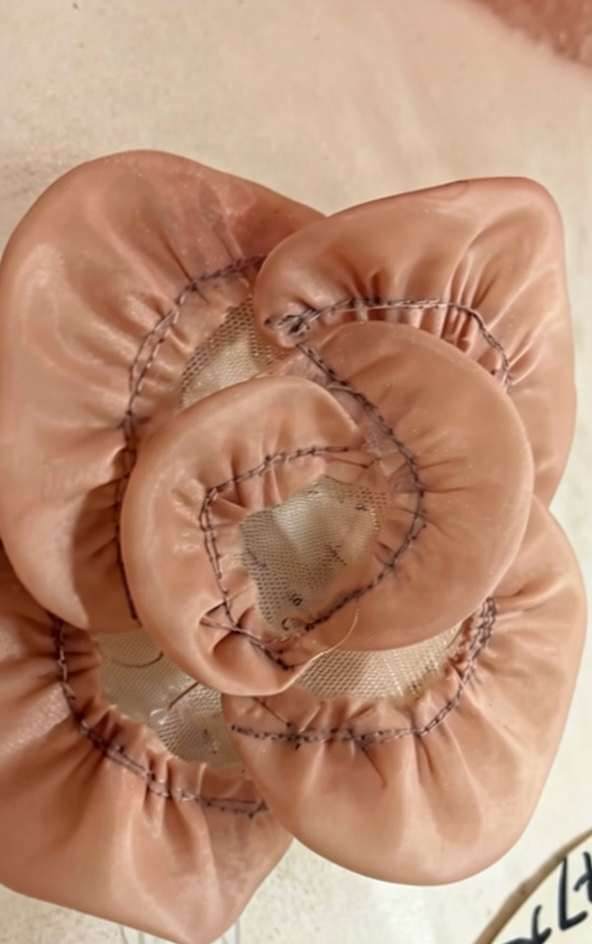 A stack of completed hand-gathered chiffon flowers in champagne pink, ready to be embellished with beaded centers