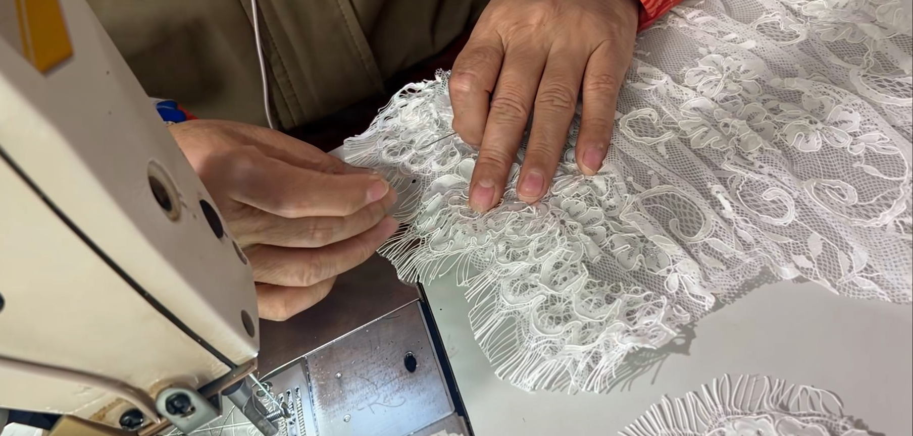 Ivory eyelash lace being stitched on a sewing machine for a bridal gown