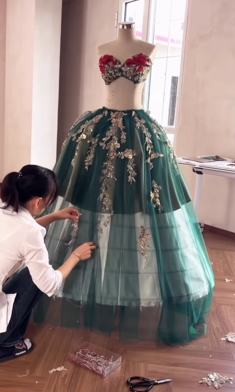 Tailor adjusting green tulle ball gown skirt