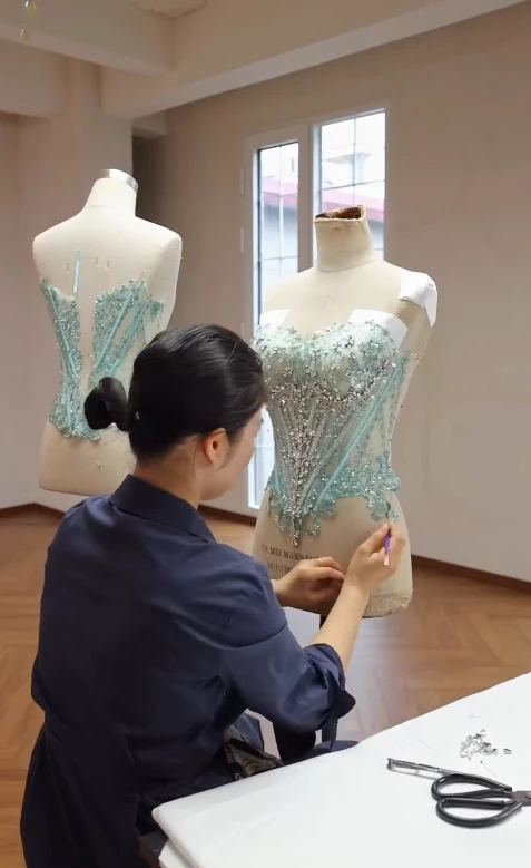 Tailor fitting the hand beaded bodice of a mint green ball gown on a dress form