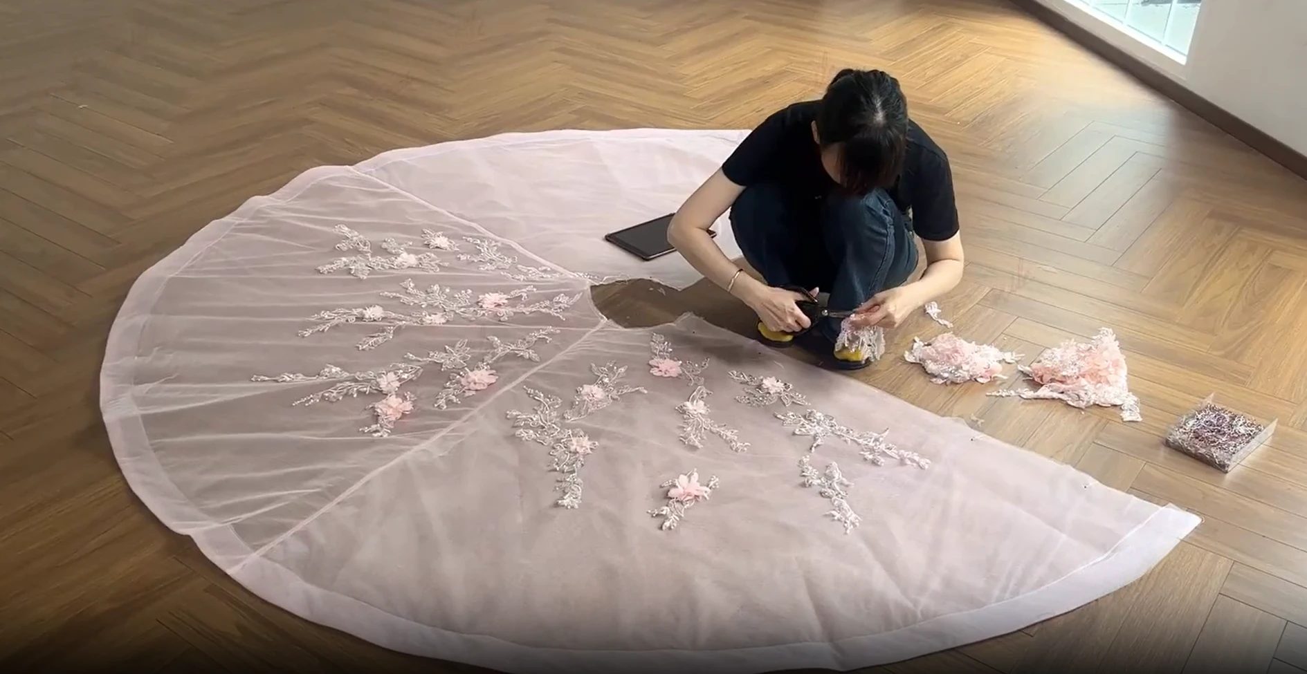 Tailor working on a large pink tulle train panel for a couture ball gown