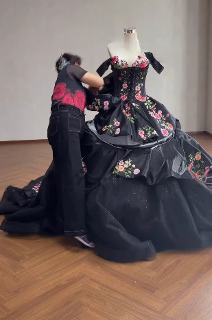 Fitting and adjusting the black rose gown on the wearer